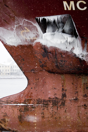 Part of the keel of a large red ship with an ice-covered anchorの写真素材
