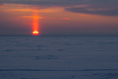 Sunset with a halo in winter, reflected in the seaの写真素材