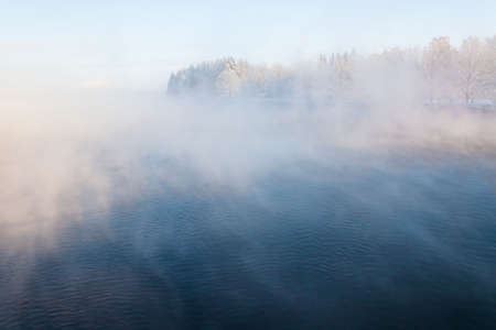Fog winter landscape on the river Fabulous misty view of lake Frosty morning. Cold weather background concept. Abstract minimalistic picture. Christmas and New Year holiday greeting cardの写真素材