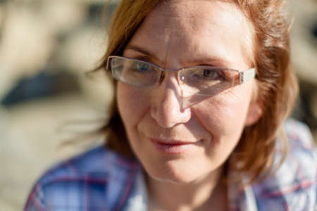 Portrait of happy mature woman wearing eyeglasses and looking at camera. Closeup face of smiling beautiful maddle aged natural woman. Retired blondy person in casualsの写真素材