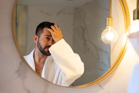 man in bathrobe looking at himself in the mirror.の写真素材