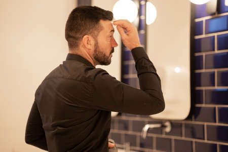 Businessman looking at himself in the bathroom mirror.