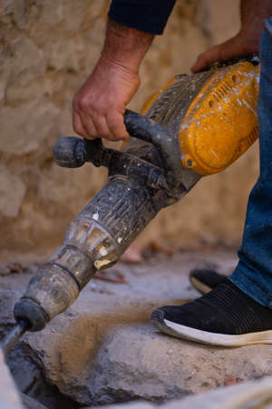 construction site worker with drilling machine removing the ground.