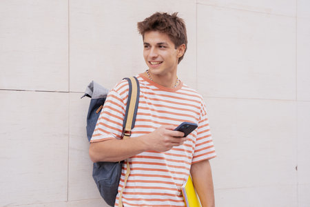 Happy student on campus using a social media app with smartphone outdoors.の写真素材