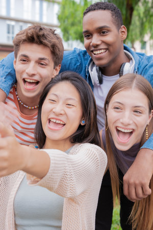 Vertical portrait Multiracial group of student friends laughing while taking a selfieの写真素材