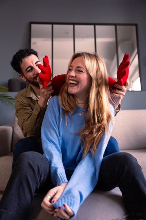Vertical portrait Valentines Day. Young couple sitting on a sofa holding a heart.の写真素材