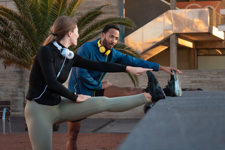 Young smiling couple with sports headphones doing stretching.
