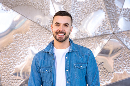 Portrait young caucasian smiling man with arms crossed outdoors.の写真素材