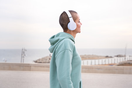 Side view smiling sporty woman with headphones standing outdoorsの写真素材