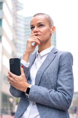 Caucasian business woman using an app on her smartphone outdoors.の写真素材