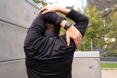Rear view male runner in warm-up stretch for running or cardio exercise.の写真素材