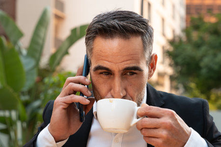 Portrait of a smiling businessman talking with a smartphone outdoors.の写真素材