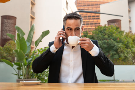 Portrait of a smiling businessman talking with a smartphone outdoors.の写真素材