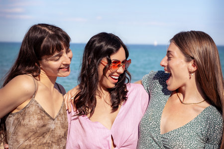 Portrait of three female friends looking at camera on the beach having fun.の写真素材