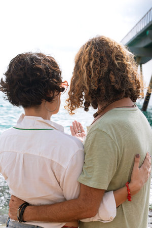 Rear view two happy friends on the beach on vacation,looking at the sea.の写真素材