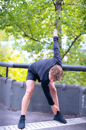 Active and fit male runner in warm-up stretch for running or cardio exerciseの写真素材