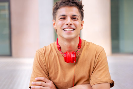 Single portrait young man smiling with arms crossed looking at camera outdoorsの写真素材