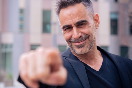 Confident and smiling business man pointing forward looking at camera outdoorsの写真素材