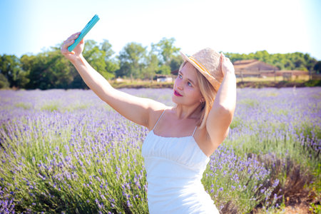 Young caucasian woman taking a selfie in lavender fieldの写真素材