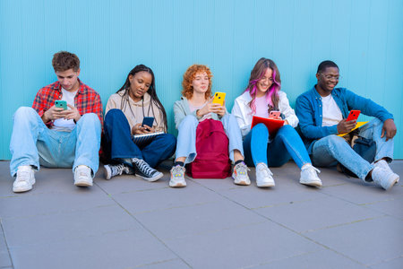 Diverse young people sitting outdoors using smartphonesの写真素材
