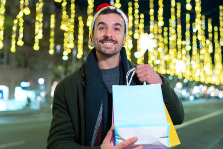 Smiling man in Santa Hat Holding Christmas Shopping Bagsの写真素材