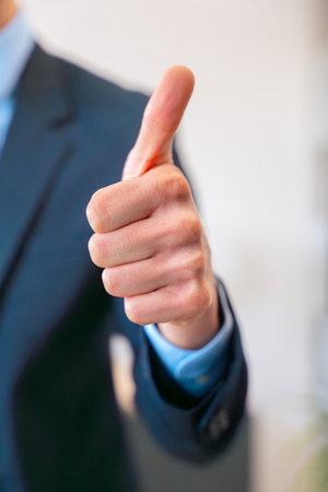 Unrecognizable businessman smiling and giving thumbs up gesture in suit.Verticalの写真素材