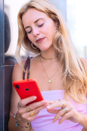 Blonde Woman Using Smartphone Outdoors in Urban Setting.Vertical