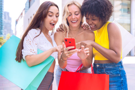 Three excited friends celebrating outdoors while looking at a smartphone.の写真素材