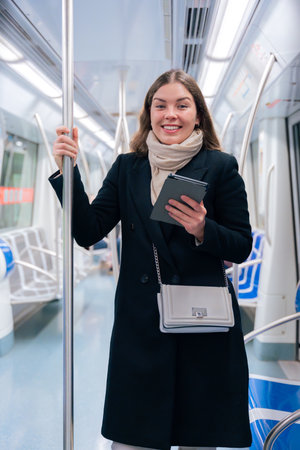 Young Woman Reading on E-Reader While Commuting on Subway.の写真素材