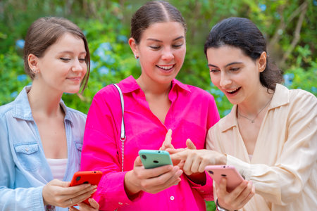 Excited Young Women Sharing Content on Smartphones Outdoorsの写真素材