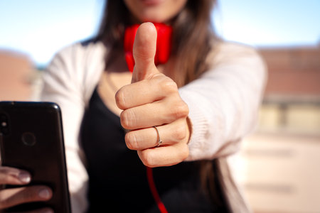 Unrecognizable woman pointing finger up looking at camera outdoors