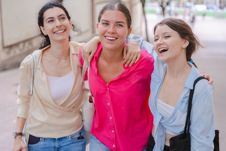 Three teenagers chatting outdoors, smiling and walking together happily