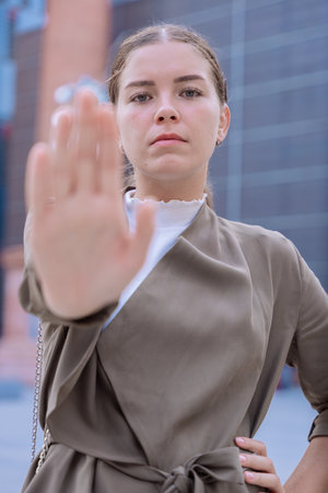 Serious young woman making stop gesture with hand in modern urban setting.の写真素材