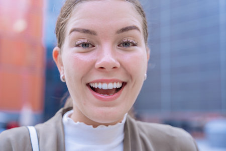 Close-up Happy Caucasian young woman looking at camera and smiling in urban settingの写真素材