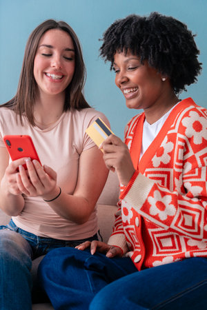 Two happy women sitting on couch smiling while looking at smartphone screen
