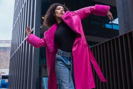 Elegant dancer in a pink coat performing artistic movements in an urban settingの写真素材