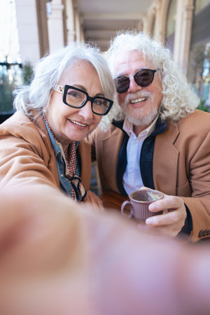 Caucasian senior couple smiling and taking selfie with smartphone outdoorsの写真素材