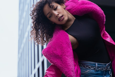 Elegant dancer in a pink coat performing artistic movements in an urban setting