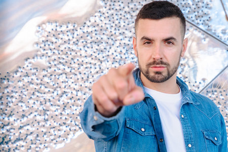 Serious man pointing at camera with focus gesture and abstract background