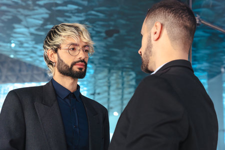 Two businessmen in serious conversation inside modern office with glass wallsの写真素材