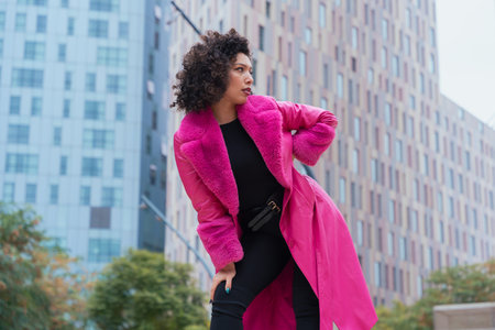 Elegant dancer in a pink coat performing artistic movements in an urban setting