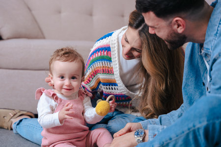 Happy family playing with baby girl on floor in cozy home living room interiorの写真素材