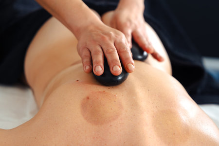 Hot stone massage therapy on back in spa wellness treatment session