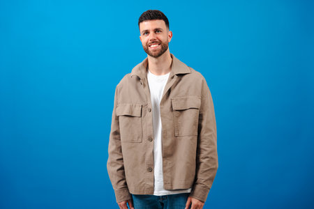 Young bearded man smiling standing on blue background in casual outfit