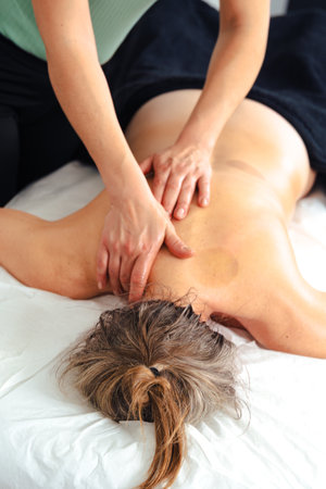 Close up of massaging client upper back gently on white massage indoorsの写真素材