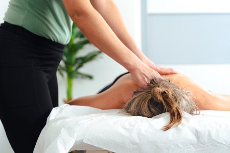 Therapist giving relaxing back massage to caucasian woman in wellness spa clinicの写真素材