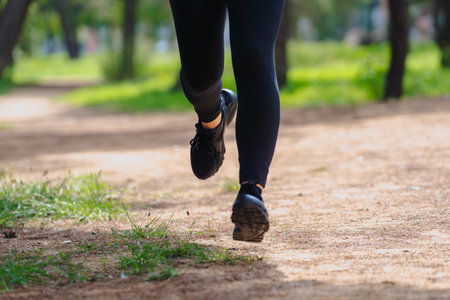 Close up of woman running on dirt path outdoors in green park vertical format