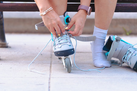 Person tying roller skate laces on street bench, preparing footwear.の写真素材