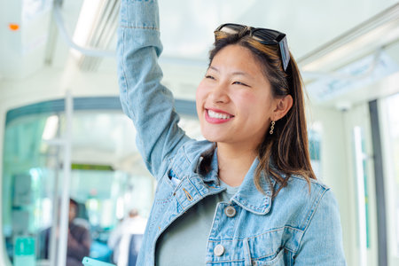 Smiling woman standing inside public transport holding the handrail.の写真素材