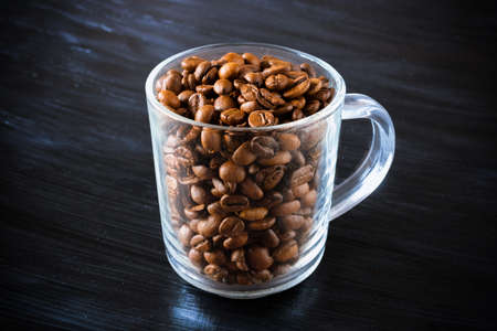 Transparent cup full of brown coffee beansの写真素材